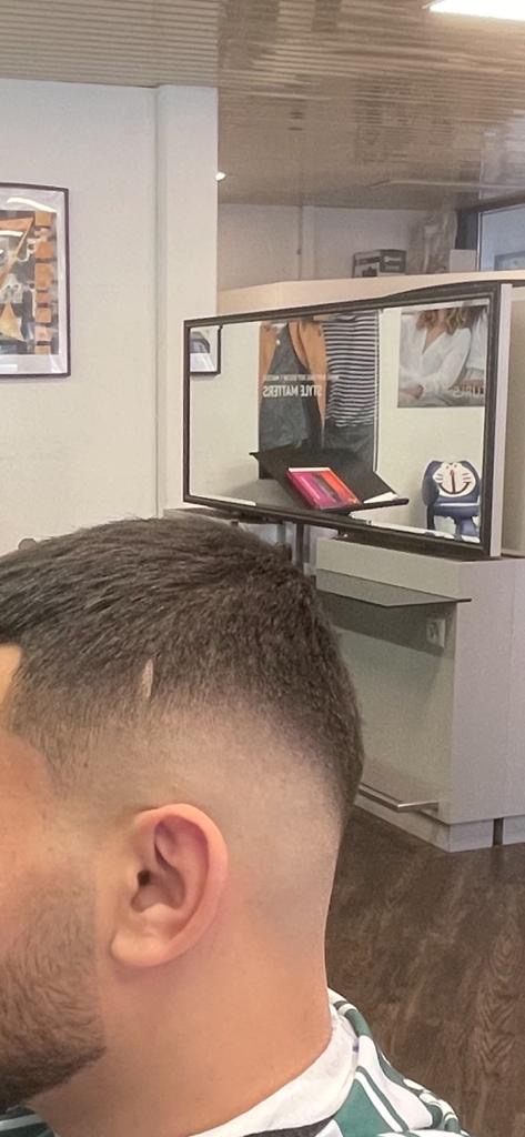 Kurzer Fade von der Seite, im Hintergrund der Salon mit Spiegel